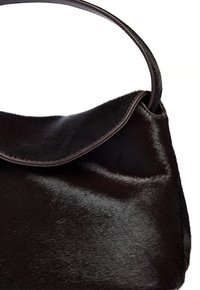 Svart läderhandväska med en slät, texturerad yta. Har en rundad topp och ett enda läderhandtag. Minimal sömnadsdetalj.