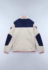 Fleece jacket featuring beige body, navy blue shoulders and sleeves, red trim at collar and hem, and emblem on left sleeve.