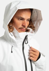 Witte waterdichte jas met een hoge kraag en capuchon, voorzien van verstelbare trekkoorden, een zwarte rits en elastische manchetten voor een veilige pasvorm.