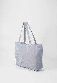 Stripet tekstil totebag med to lange håndtak, med rektangulær form og en teksturert overflate i marineblå og hvite farger.