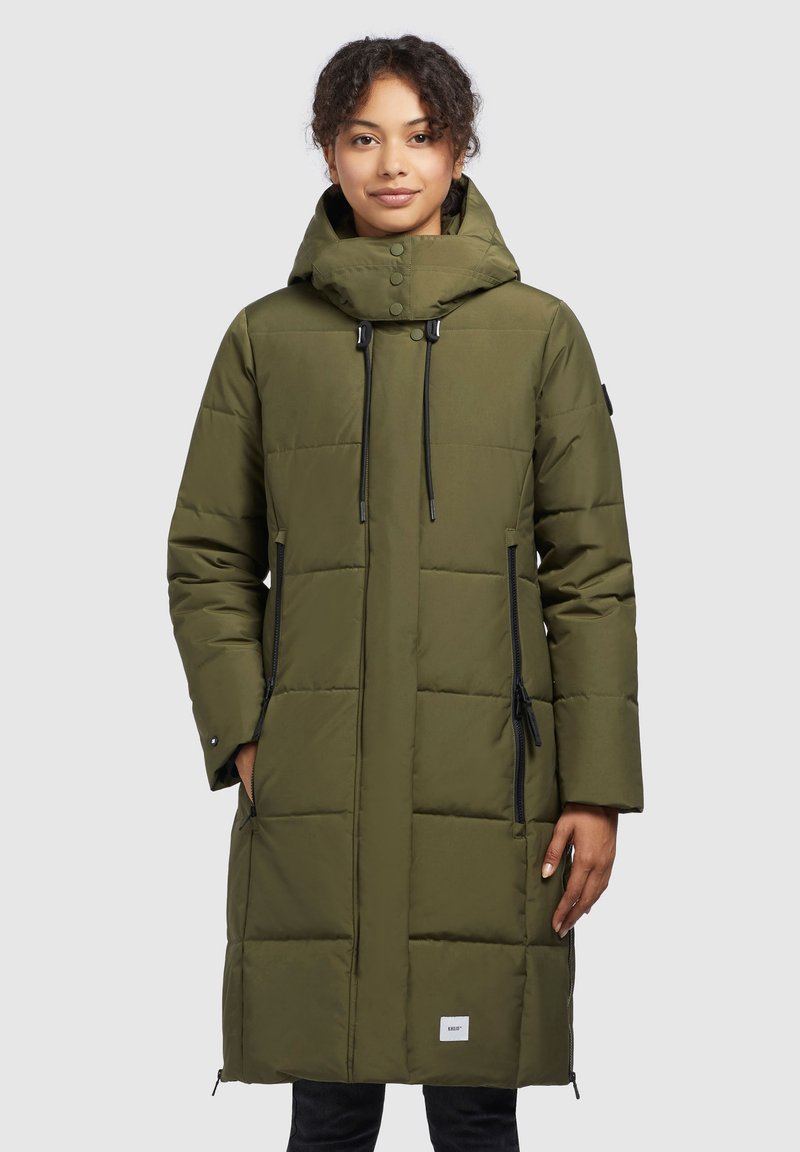 Olive green padded coat with a hood, featuring black drawstrings, zippered pockets, and a square pattern. Length extends to mid-calf.