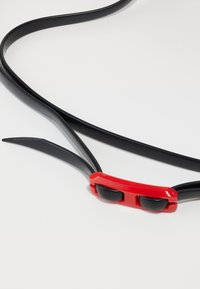 Black silicone belt featuring a red clasp with two circular black accents, smooth texture, and flexible design.