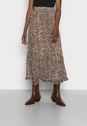 Mujer con falda midi de estampado de leopardo beige y marrón con cintura elástica y botines marrones.