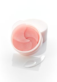 Coussins oculaires en hydrogel rose dans un récipient blanc, accompagnés d'une spatule applicatrice transparente. Les coussins présentent une surface texturée avec un motif en spirale.