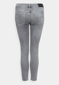 Jeans ajustados de mezclilla gris claro, con cintura alta, diseño de cinco bolsillos y un ligero deshilachado en los dobladillos de los tobillos.