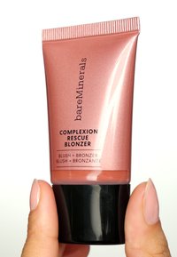 Rosenfärgad trycktub med svart bas. Etiketten lyder "Complexion Rescue Blonzer," vilket indikerar rouge och bronzer-funktioner. Slät textur.