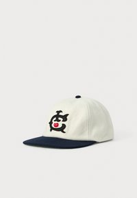 Hvid baseballkasket med mørkeblå skygge og broderet sort og rød stiliseret dyrelogo på frontpanelet, vist på hvid baggrund.