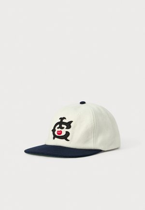 White baseball cap with dark blue brim and embroidered black and red stylized animal logo on the front panel, shown on white background.