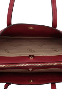 Rode leren handtas met gouden beslag, ritssluiting aan de voorkant en stoffen voering met een reliëf logo patroon. Open interieurontwerp.