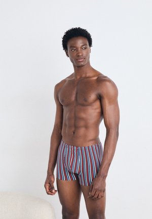 Gestreifte Boxer in Blau, Rot und Weiß; elastischer Bund; enganliegendes Design; glattes Material; getragen von einer männlichen Figur mit athletic Bau.
