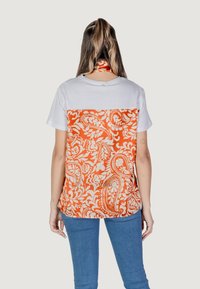 Tenký tričko s krátkým rukávem s bílou horní částí a oranžovým paisley vzorem na spodní části. Bavlněný materiál, klasický střih, ležérní design.