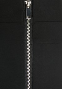 Black garment with a prominent silver zipper on the front, featuring a smooth, stretchy fabric and clean, sleek lines.