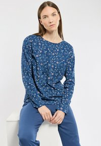 Haut à manches longues bleu avec un motif floral en rose et blanc. Fabriqué en tissu doux, il possède un col rond et une coupe décontractée.