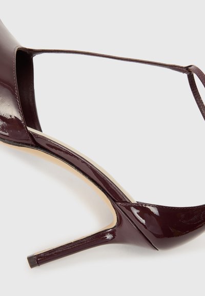 Μπορντό παπούτσι με λουστρίνη, ψηλή γόβα με ανοιχτό μπροστινό μέρος, κοφτερό σχέδιο και λεπτή λουρίδα στον αστράγαλο. Διαθέτει λεπτή γαλάζια γόβα.