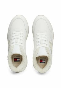 White sports shoes with soft fur lining, featuring a smooth leather upper, flat laces, and subtle striped accents on the sides.