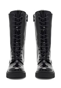 Must musta kõrgema säärega mustad patendiga saapad, millel on lamedad tallad, nöörid esiosas, metallist silmad ja lukud külgedel.