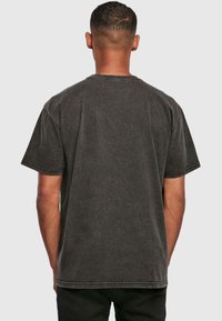 Camiseta de algodón negra con un corte relajado, mangas cortas y cuello redondo, con detalles de costura visibles en las costuras.