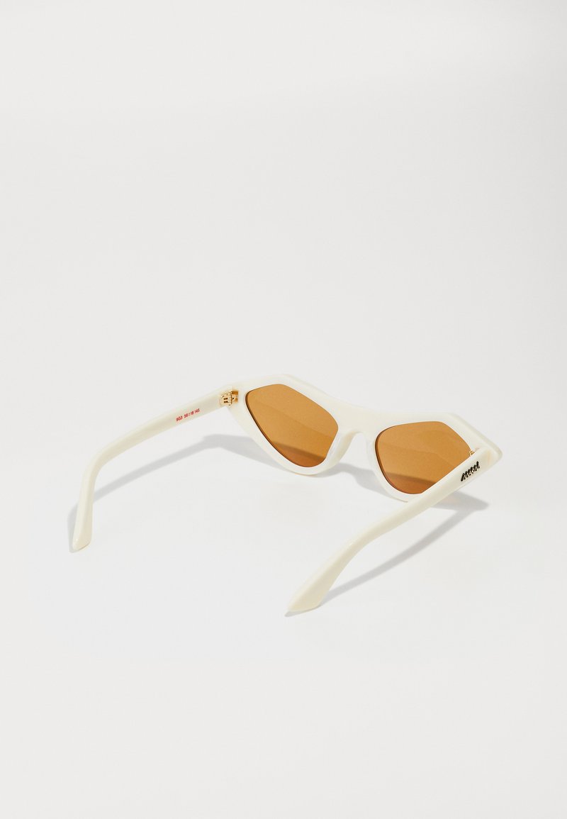Occhiali da sole bianchi angolari con montatura sottile, lenti marroni sfumate e dettagli in metallo color oro. Disponibili con finitura opaca.