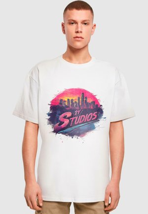 White cotton t-shirt featuring a colorful graphic of a city skyline with the text "2Y STUDIOS" in pink and blue, against a circular background.