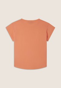 Top de mangas cortas y cuello redondo en un suave color durazno. Textura lisa con un dobladillo ligeramente curvado en la parte inferior. Sin patrones ni adornos.