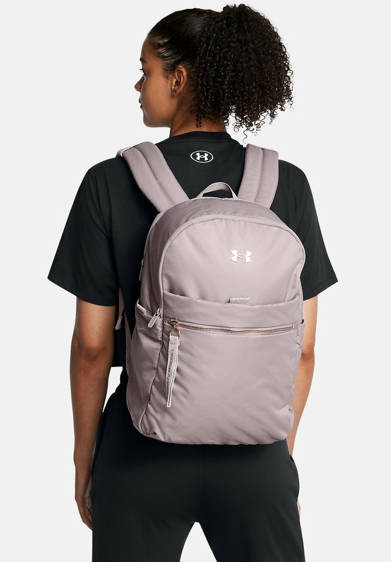 Mochila de color rosa claro con correas de hombro acolchadas, un bolsillo frontal con cremallera y acento de logo. Fabricada con un tejido suave y duradero de textura lisa.