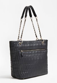 Sac à main en cuir matelassé noir avec des anses en chaîne dorée et une poche zippée extérieure à l'avant, exposé sur un fond blanc.