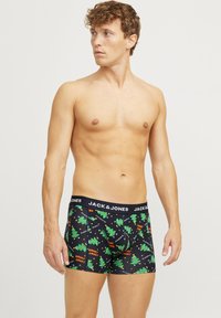 Boxers noirs avec un motif de sapin de Noël en vert et orange. Ceinture élastique avec le logo "JACK & JONES". Tissu doux, design ajusté.