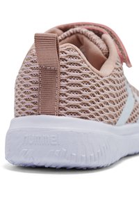 Baskets en tissu mesh rose avec semelle blanche épaisse, languette arrière et bride velcro partiellement visible pour la fermeture.