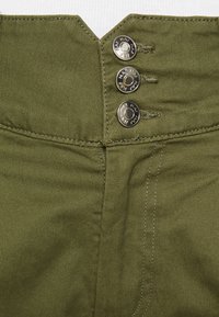 Pantalon vert olive à taille haute, avec trois boutons métalliques et des détails de couture visibles sur un tissu lisse et texturé.