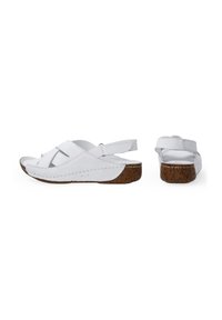 Witte sandalen met een kurken zool, voorzien van gekruiste banden en een achterband voor ondersteuning. Soepele textuur en minimale stikseldetails.