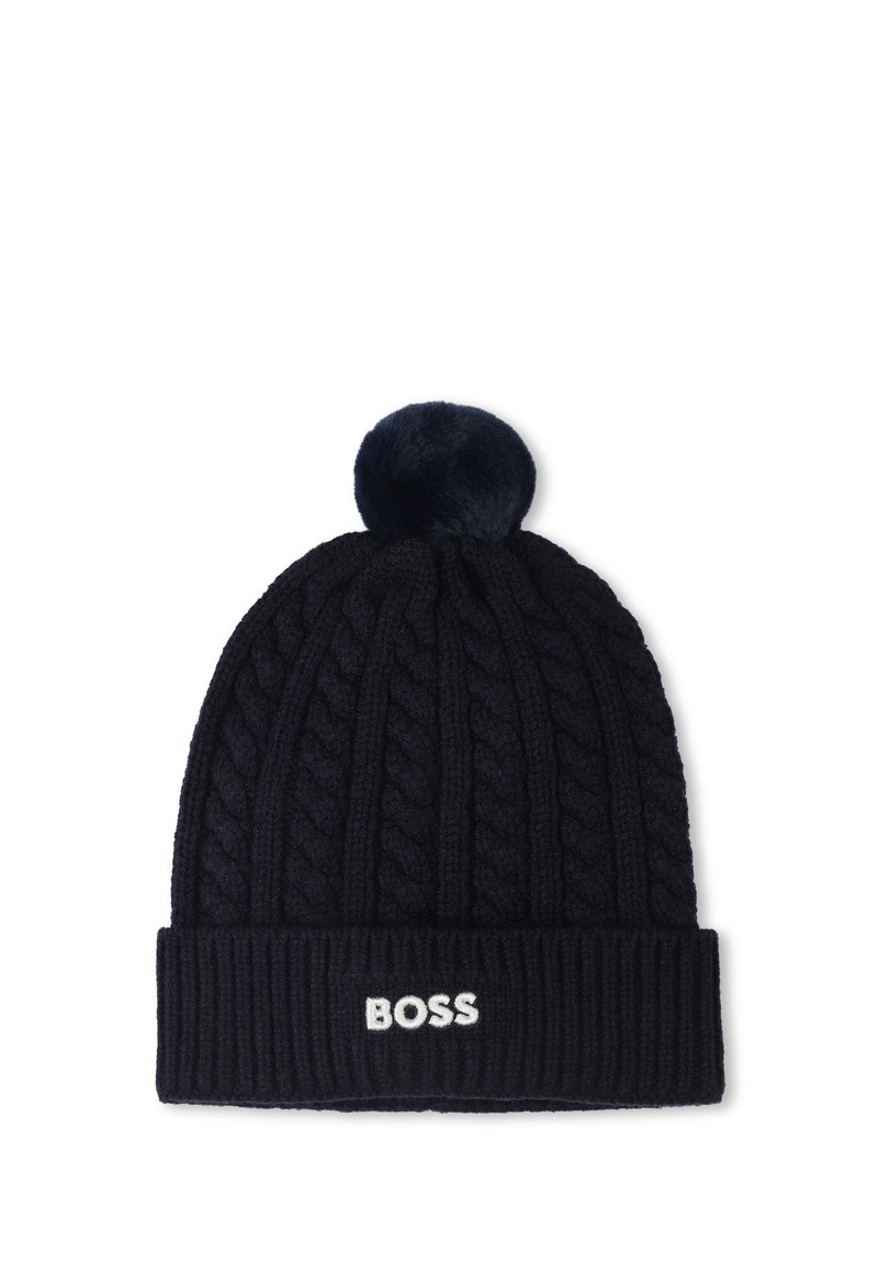 Bonnet tricoté bleu marine avec un motif de câble, une bordure côtelée et un pompon duveteux sur le dessus. Logo "BOSS" affiché sur le revers en blanc.