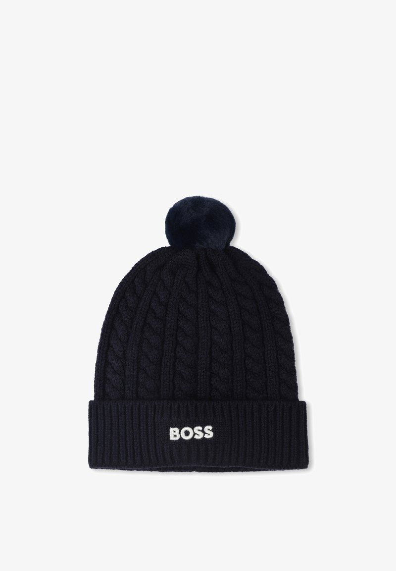 Bonnet tricoté bleu marine avec un motif de câble, une bordure côtelée et un pompon duveteux sur le dessus. Logo "BOSS" affiché sur le revers en blanc.