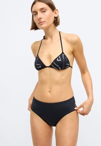 Μαύρο μπικίνι με τριγωνικό τοπ που διαθέτει λεπτομέρειες σχεδίου και λεπτές τιράντες. Ο ψηλόμεσος πάτος είναι απλός και λεία στην υφή.