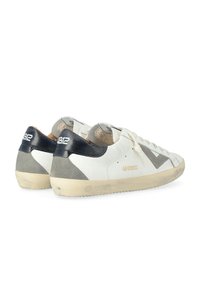Baskets en cuir blanc avec des accents gris et noirs. Design low-top, semelle texturée et détail de logo sur le talon. Marques d'usure notables.
