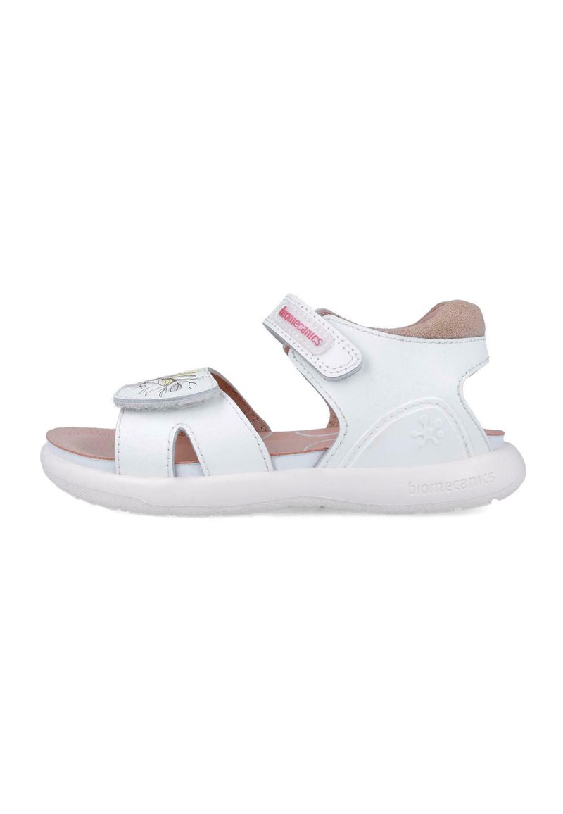 Sandal bianca con numerosi fori, un design floreale sulla cinghia, chiusura regolabile con Velcro e suola imbottita. Presenta un logo sul lato.