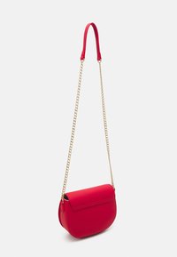 Červená kabelka s hladkým povrchem, zaobleným tvarem a zlatým řetízkovým popruhem. Má klopový uzávěr a pevný design bez vzorů.