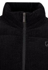 Mustast maneesrikangast jakk kõrge kraega, täispikendusega tõmblukuga, tekstureeritud vertikaalsete soonikutega ja vasakul küljel tikitud logoga.