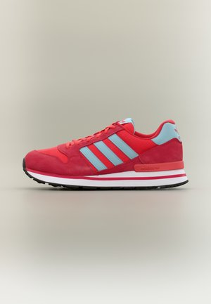 Raudonas ir šviesiai mėlynas sportinis batelis iš tinklelio ir zomšos medžiagų, su trimis mėlynomis juostelėmis, baltu viduriniu padu ir juodu guminiu išoriniu padu.