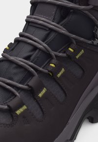 Μαύρο μποτάκι πεζοπορίας με γκρι κορδόνια από σκοινί, περασμένα μέσα από δερμάτινα ανοίγματα με κίτρινη ραφή και γλωττίδα από υφαντό υλικό με υφή.