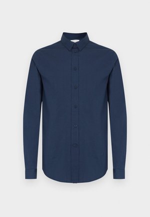 Marineblauw shirt met lange mouwen, een button-down kraag, gestructureerde stof en zes knopen aan de voorkant. Rondere zoom en manchetten met één knoop.