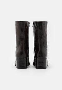 Stivali neri in pelle sul collo del piede con una texture liscia, punta quadrata e tacco a blocco basso; presentano due cerniere sul retro per una facile vestibilità.