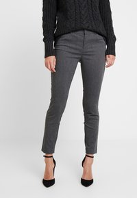 Grå skräddarsydda byxor i ett slätt tyg, med en elegant passform och ankellång längd, kombinerade med svarta högklackade skor.