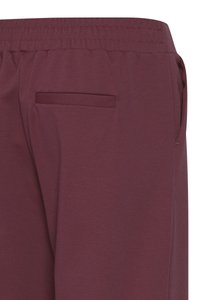 Bordo trenirke s elastičnim pojasom, s stražnjim džepom i glatkom, teksturiranom završnom obradom.