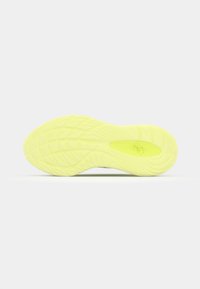 Semelle en caoutchouc d'une chaussure, principalement jaune néon avec des motifs texturés et des rainures pour l'adhérence, comportant un logo central.