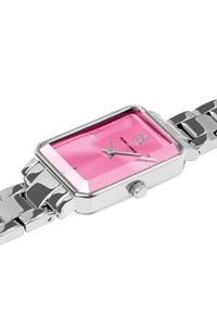 Stačiakampis sidabrinis metalinis laikrodis su ryškiai rožiniu ciferblatu, sidabriniais valandų ir minučių rodyklėmis bei grandinėlės apyranke. Yra karūnėlė šone.