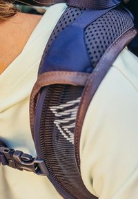 Sangle de sac à dos en mesh et tissu violet foncé, dotée d'une boucle à clip, de motifs texturés et de détails de conception respirants.