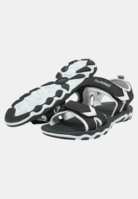Sport sandaler i svart och vitt. Har justerbara Velcro-remmar, strukturerad sula och vadderad fotbädd. Lättviktig och hållbar design.