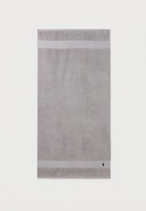 Serviette rectangulaire gris clair avec deux bandes horizontales près des bords et un petit logo sombre dans le coin inférieur droit.