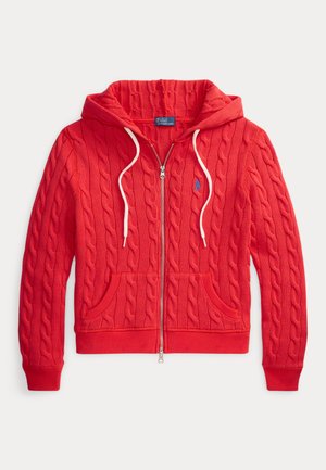 Sweat à capuche rouge en maille torsadée avec fermeture éclair, cordons blancs, poches avant, poignets côtelés et petit logo bleu brodé sur la poitrine.