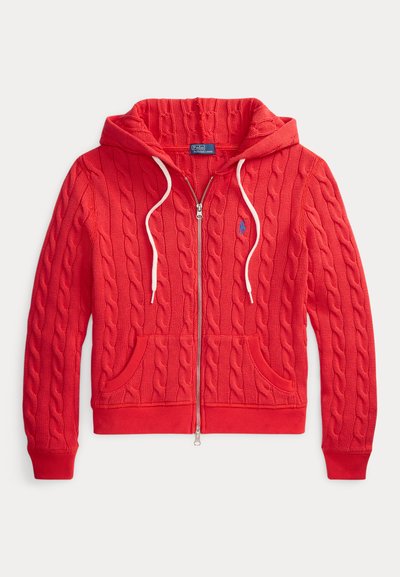 Rode kabelgebreide hoodie met ritssluiting, witte trekkoorden, voorzakken, geribbelde manchetten en een klein blauw geborduurd logo op de borst.